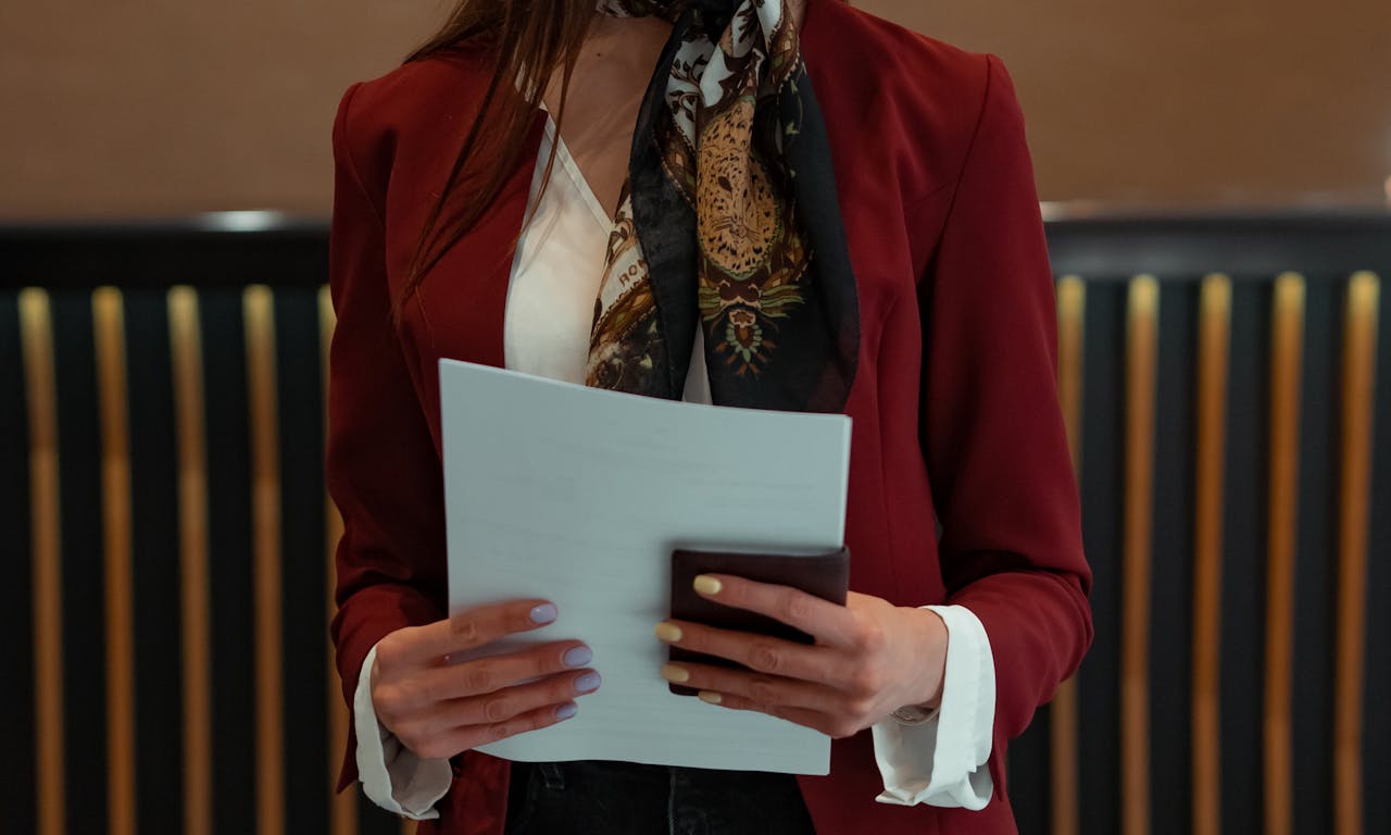 Hotel receptionist holding documents and wallet in formal attire, ready to assist guests.